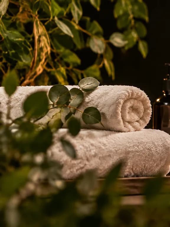 Rolled white towels and greenery in soft candlelight.